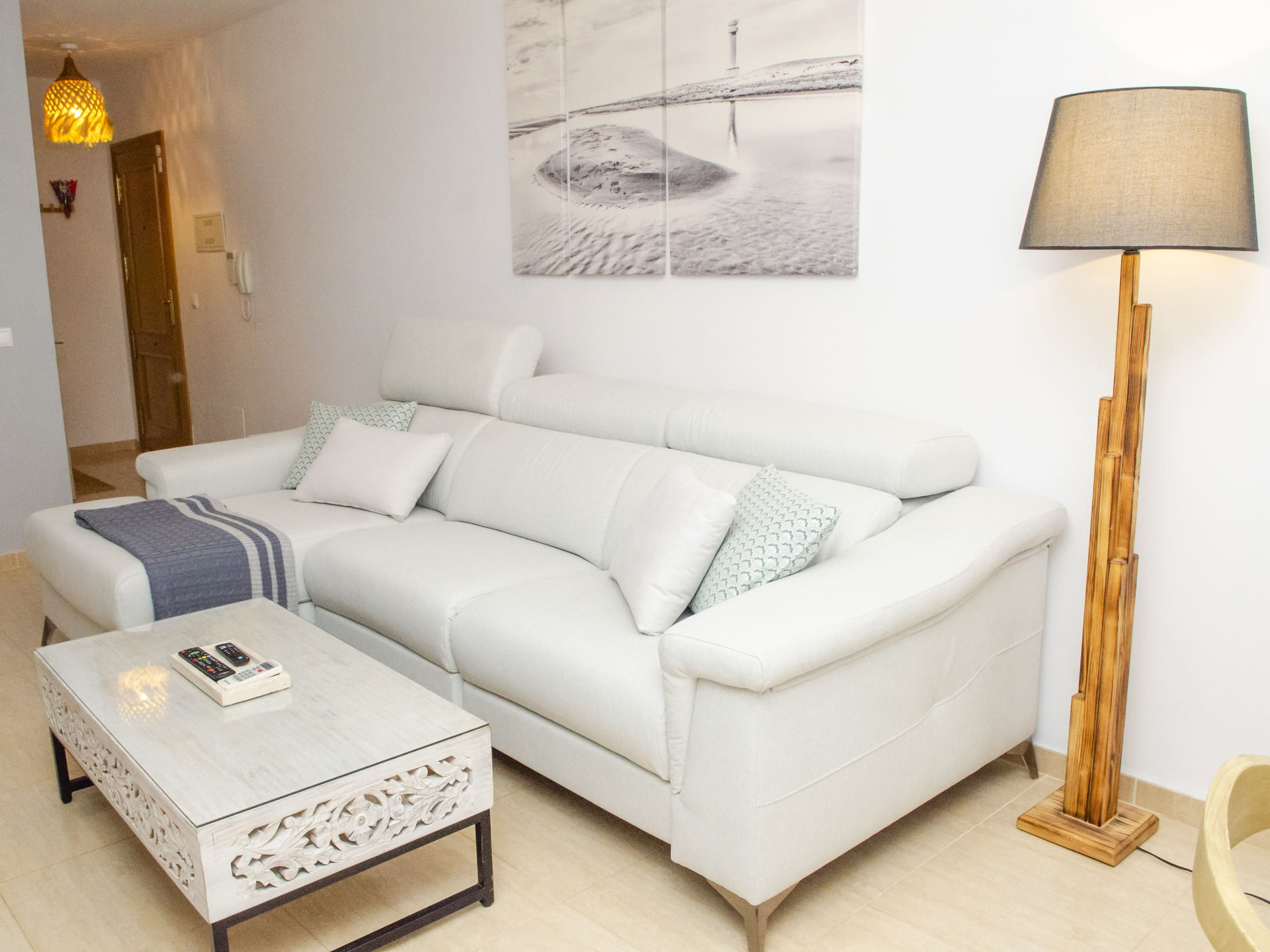 Sofá chaise longue blanco del salón con lámpara de pie de madera